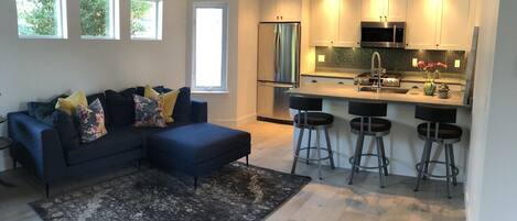 A modern kitchen with a central island, bar stools, and a refrigerator.