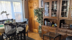 Una sala de estar con un sofá de cuero, un comedor con mesa y sillas, y un mueble de madera con puertas de vidrio.