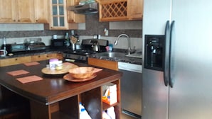Una cocina con armarios de madera, un refrigerador de acero inoxidable, una estufa y un lavamanos.