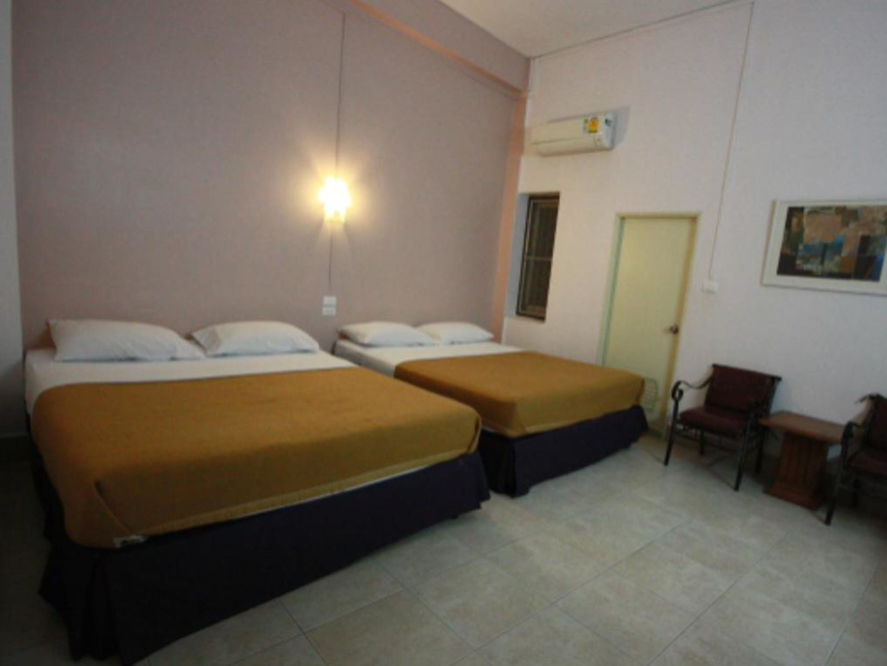 Habitación de hotel con dos camas, un escritorio, una silla y un equipo de aire acondicionado en la pared.