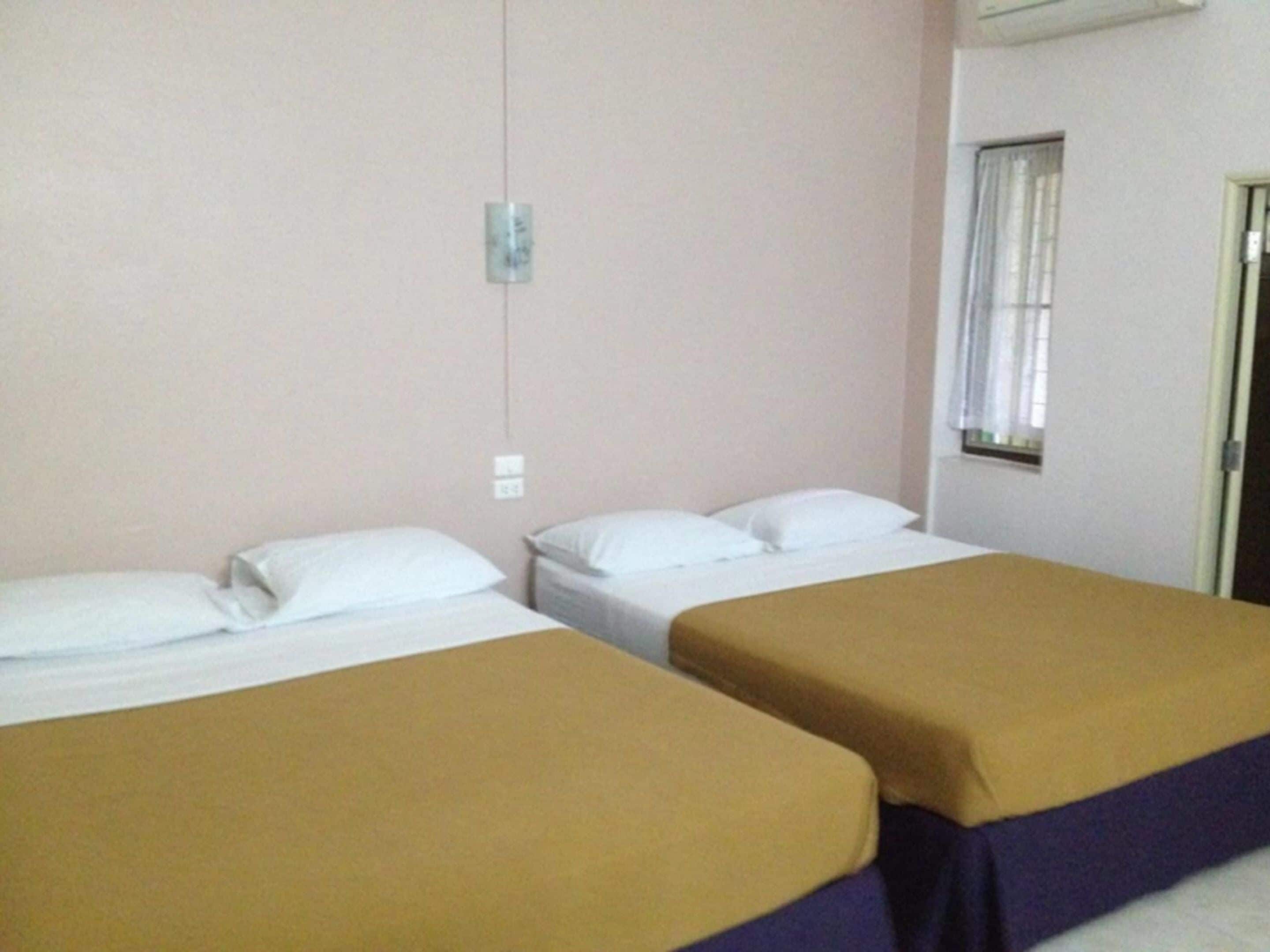 A hotel room with two beds, each with white pillows and brown bedspreads.