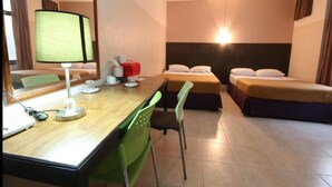 Een hotelkamer met een houten bureau, twee eenpersoonsbedden, een groene stoel en een grote spiegel.