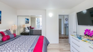A modern hotel room with a large bed, a TV, a dresser, and a bathroom visible through an open door. - Designer Renovated, One Bedroom, Free Parking, Washer/dryer, Walk To Beach (Honolulu)