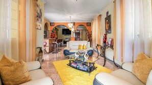 Un salón amplio con un tapete amarillo, una mesa de centro de cristal y dos sofás con cojines.