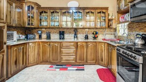 Una cocina con gabinetes de madera, microondas, estufa y cafetera.