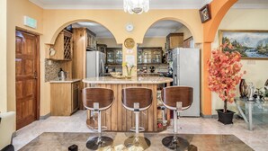 Una cocina con isla central, armarios de madera y una araña.
