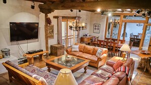 A cozy living room with a sofa set, a coffee table, and a television. - Palace Of Miracles: Hot Tub, Lounge Spaces, +Casita, mtn views,5 courtyrds,6 FPs (El Prado)