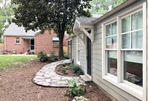A house with a stone pathway leading to the front door, surrounded by a small garden and a tree. - Best Tiny House In Town! (Raleigh)
