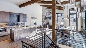 A spacious kitchen with a large island, stone accent wall, and a view of the city.