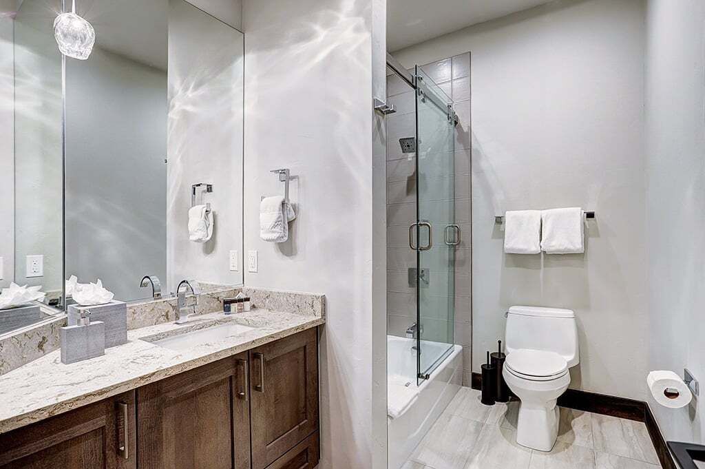 A modern bathroom with a glass-enclosed shower, a double sink vanity, and a toilet.