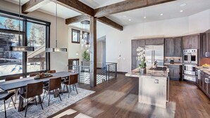 A spacious kitchen with modern appliances, a dining area with a large table and chairs, and a view of the outdoors through large windows.