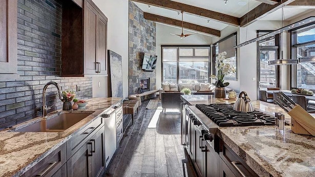 A modern kitchen with granite countertops, a central island, and a large window providing a view of the city.
