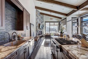 Une cuisine moderne dotée de plans de travail en granit, d’un îlot central et d’une grande fenêtre offrant une vue sur la ville.