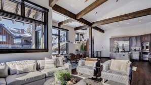 A spacious living area with a large window, a dining area, and a modern kitchen.