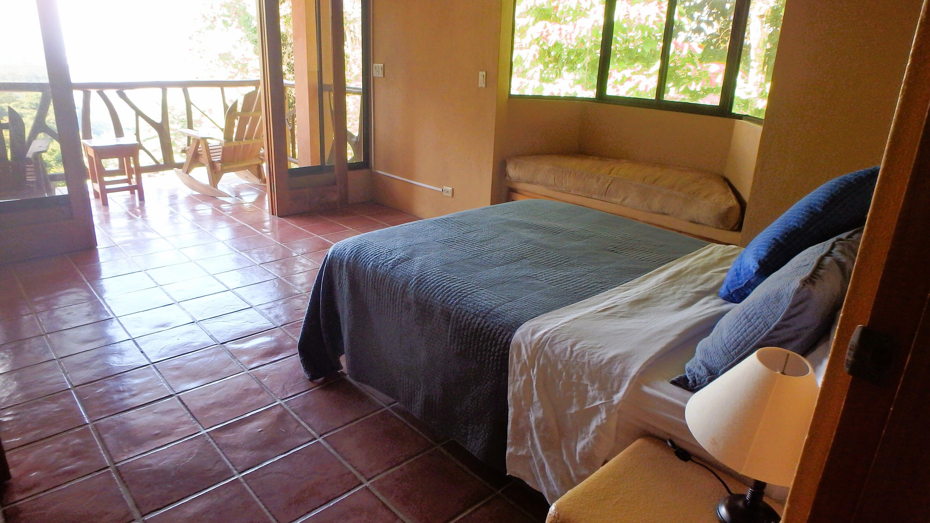 A bedroom with a bed, a chair, a table, and a window.