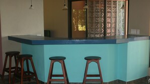 Eine Bar mit einer blauen Arbeitsplatte und drei hölzernen Barhocker.