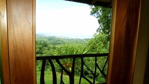 Ein hölzerner Balkon mit Blick auf eine üppige grüne Landschaft und ein Gewässer in der Ferne.