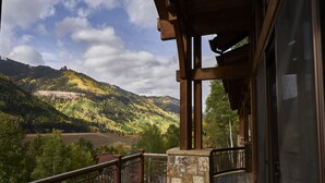 A wooden deck with a stone wall, a metal railing, and a view of a mountainous landscape. - Family, Friends and Festivals! Enjoy Telluride at its Finest! (Telluride)