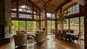 A spacious living area with a fireplace, wooden floors, and large windows offering a view of the outdoors. - Family, Friends and Festivals! Enjoy Telluride at its Finest! (Telluride)