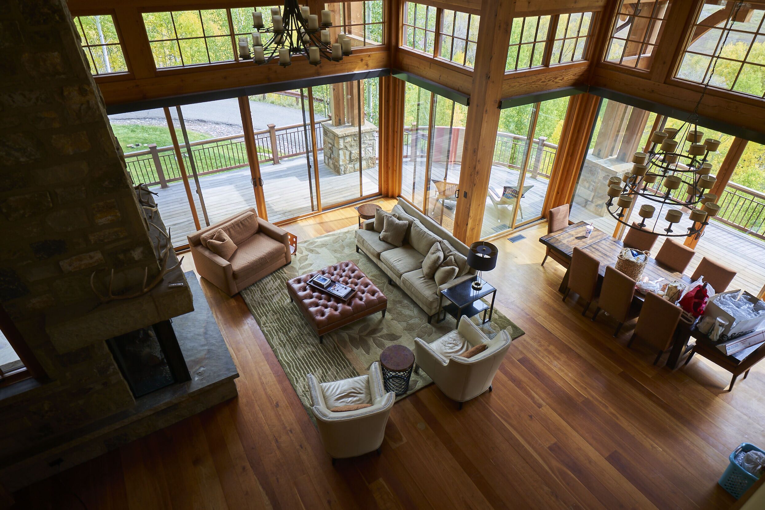 A spacious living room with a fireplace, large windows, and a dining area with a chandelier.