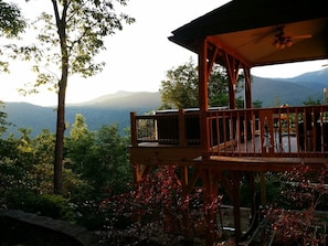 A wooden deck with a railing, overlooking a mountainous landscape.
