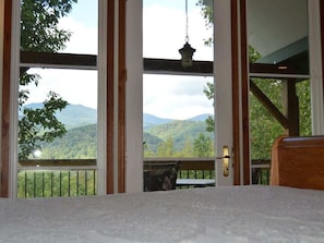 A room with a view of mountains, a hanging lantern, and a wooden bench.