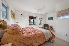 Une chambre à coucher comprenant un lit, une chaise, un bureau, une fenêtre et des œuvres d’art accrochées aux murs.