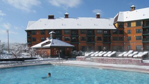 Een hotel met een zwembad, een overdekt gedeelte en een besneeuwd landschap.