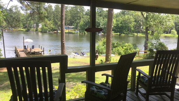A wooden deck with two rocking chairs facing a lake. - Archie's Lake Daze Cottage - No Pets (Manning)