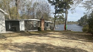 A single-story house with a garage, a small porch, and a view of a lake. - Archie's Lake Daze Cottage - No Pets (Manning)