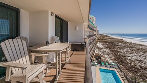 Ein Balkon mit Pool, Stühlen und Tisch mit Blick auf Strand und Meer.