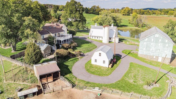 Ein Bauernhof mit Scheunen, einem Haus und einem Teich.