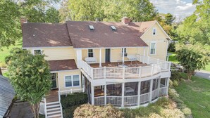 Ein zweistöckiges Haus mit überdachter Terrasse und einem kleinen Balkon.