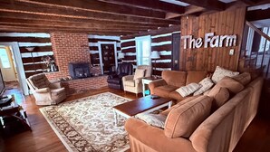 Ein gemütliches Wohnzimmer mit Kamin aus Ziegelsteinen, Holzbalken und einem großen Sofa.
