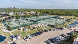 Un grand complexe de courts de tennis comprenant plusieurs terrains, un parking et des espaces verts environnants.