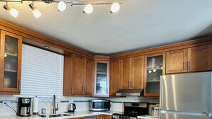 Une cuisine moderne avec des meubles en bois, des appareils en acier inoxydable et un sol carrelé.