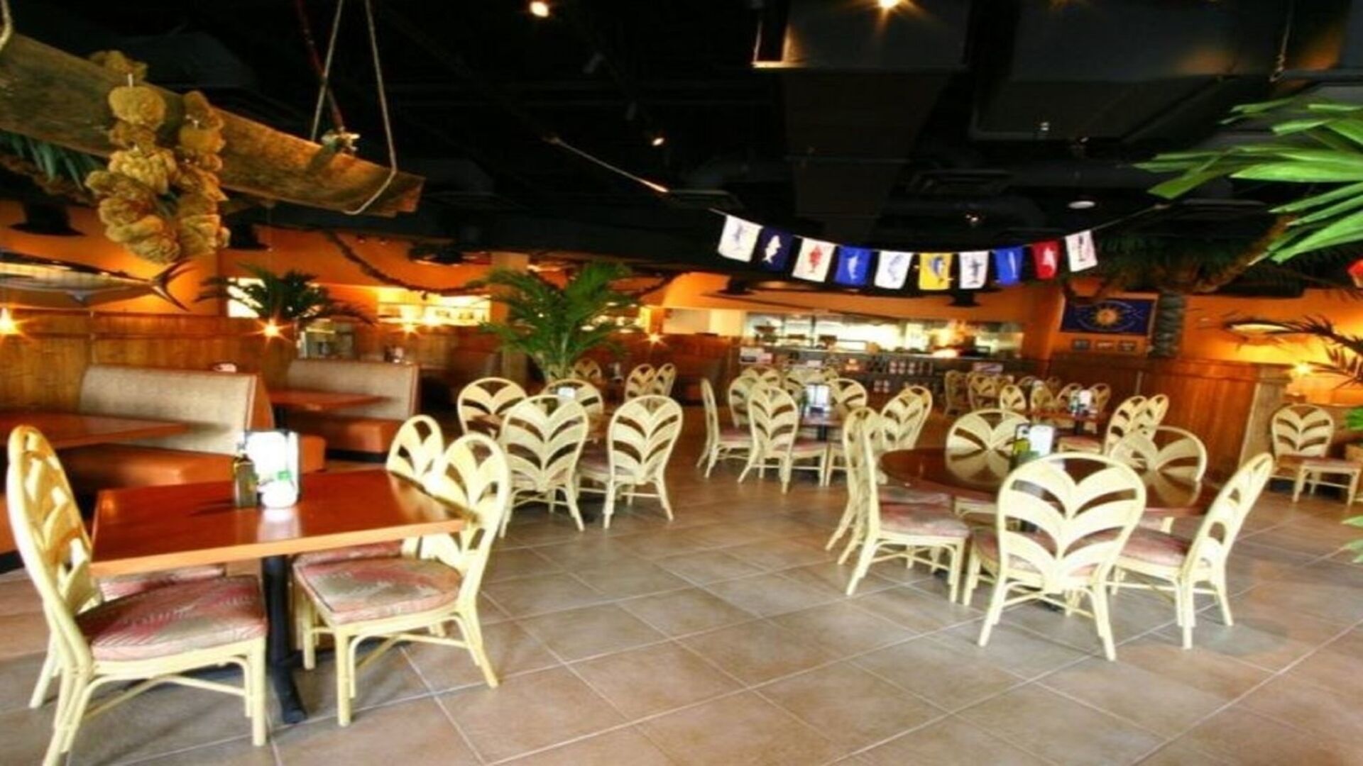 A restaurant with wooden tables and chairs, a bar area, and a ceiling with hanging decorations.