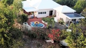 A house with a white exterior, a swimming pool, and a solar panel.