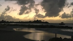 A coastal scene with a curved shoreline, a body of water, and a distant building complex.