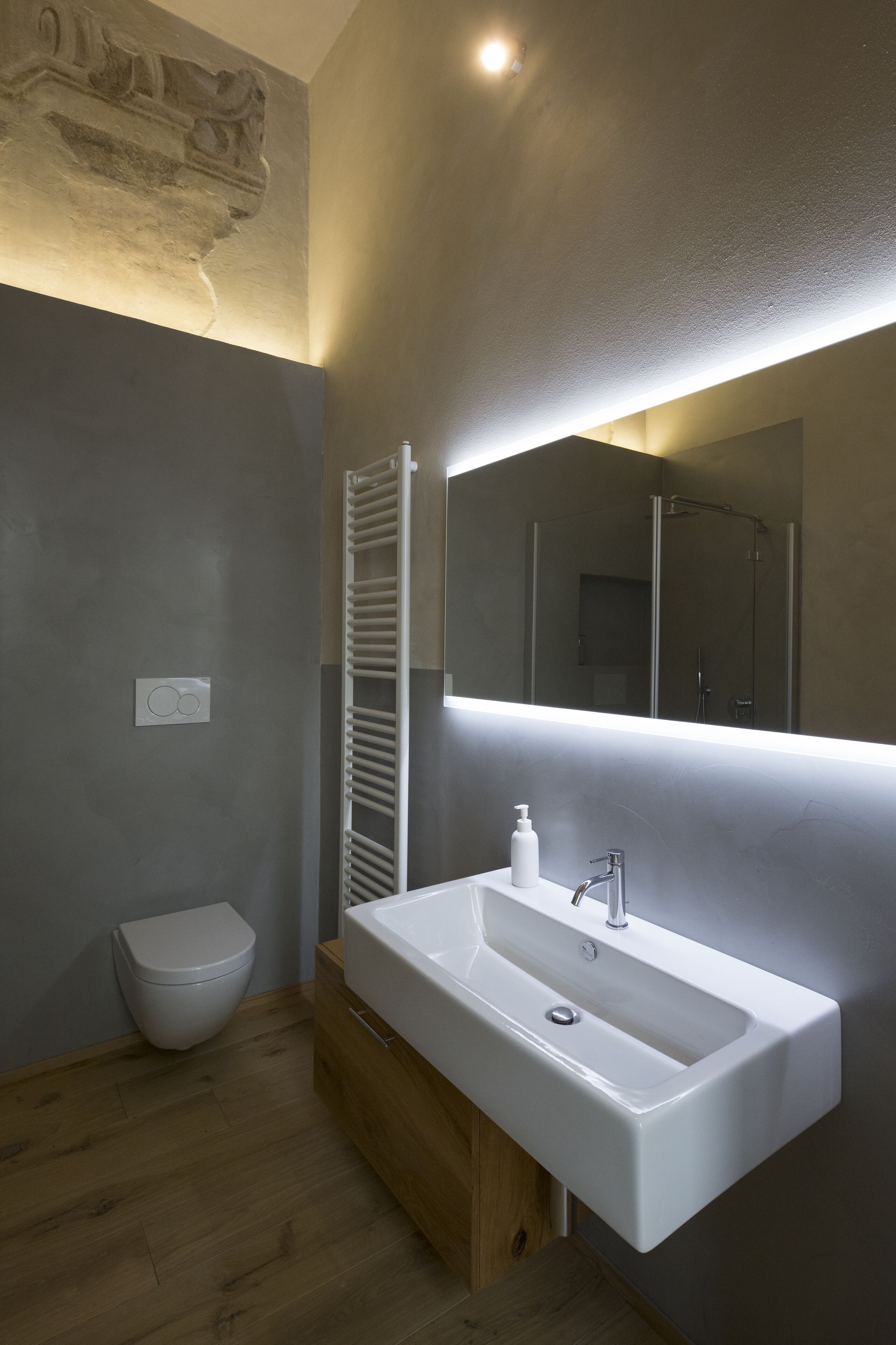 Een moderne badkamer met een wit wastafeltje, een spiegel en een douche.