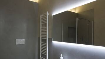Een moderne badkamer met een wit wastafeltje, een spiegel en een douche.