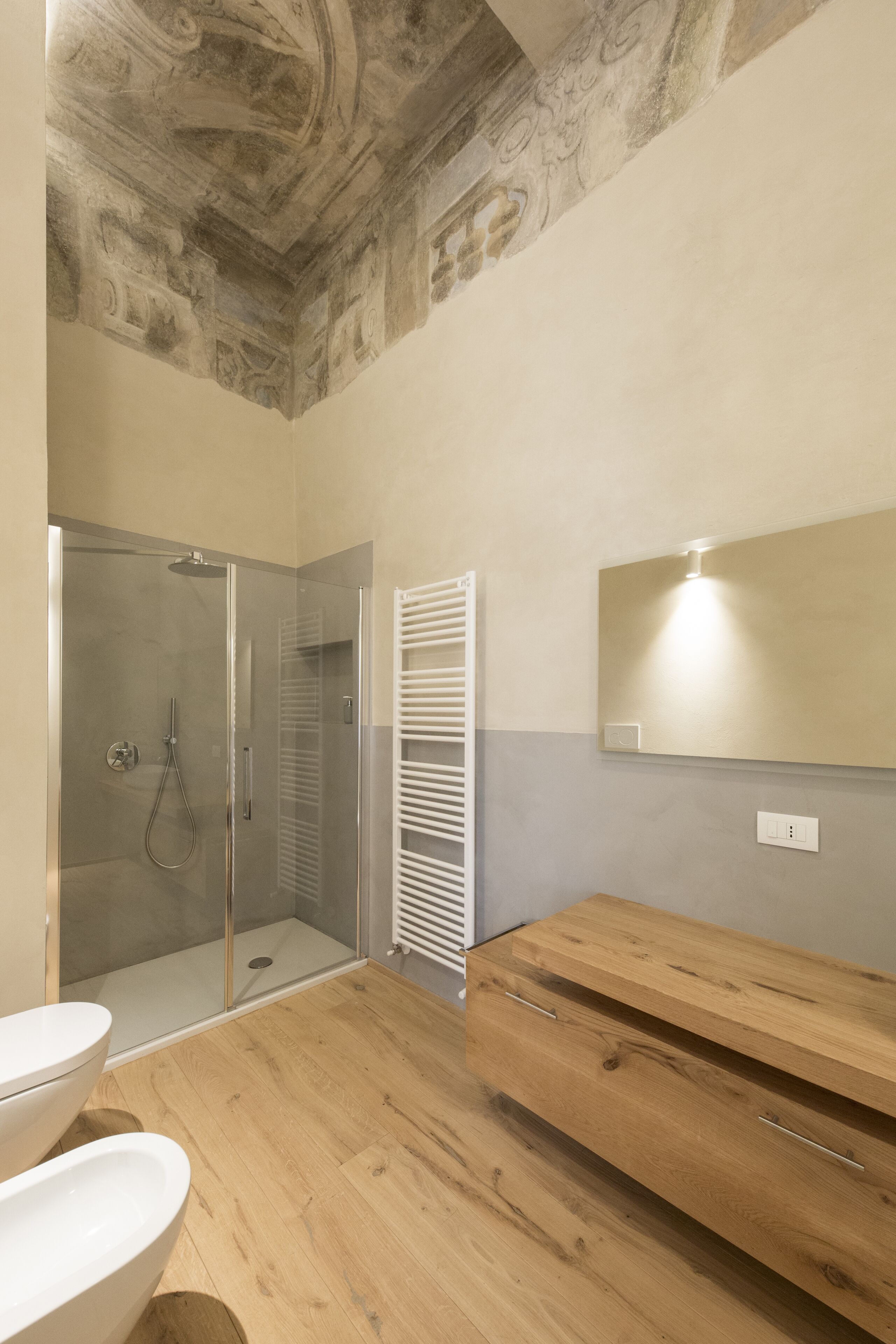 Un bagno con cabina doccia in vetro, mobile bagno in legno e lavandino in marmo.