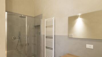 Un bagno con cabina doccia in vetro, mobile bagno in legno e lavandino in marmo.