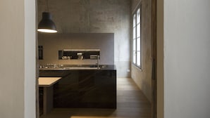 Une cuisine moderne dotée d’un plan de travail en marbre, d’un évier encastré et d’un luminaire suspendu.