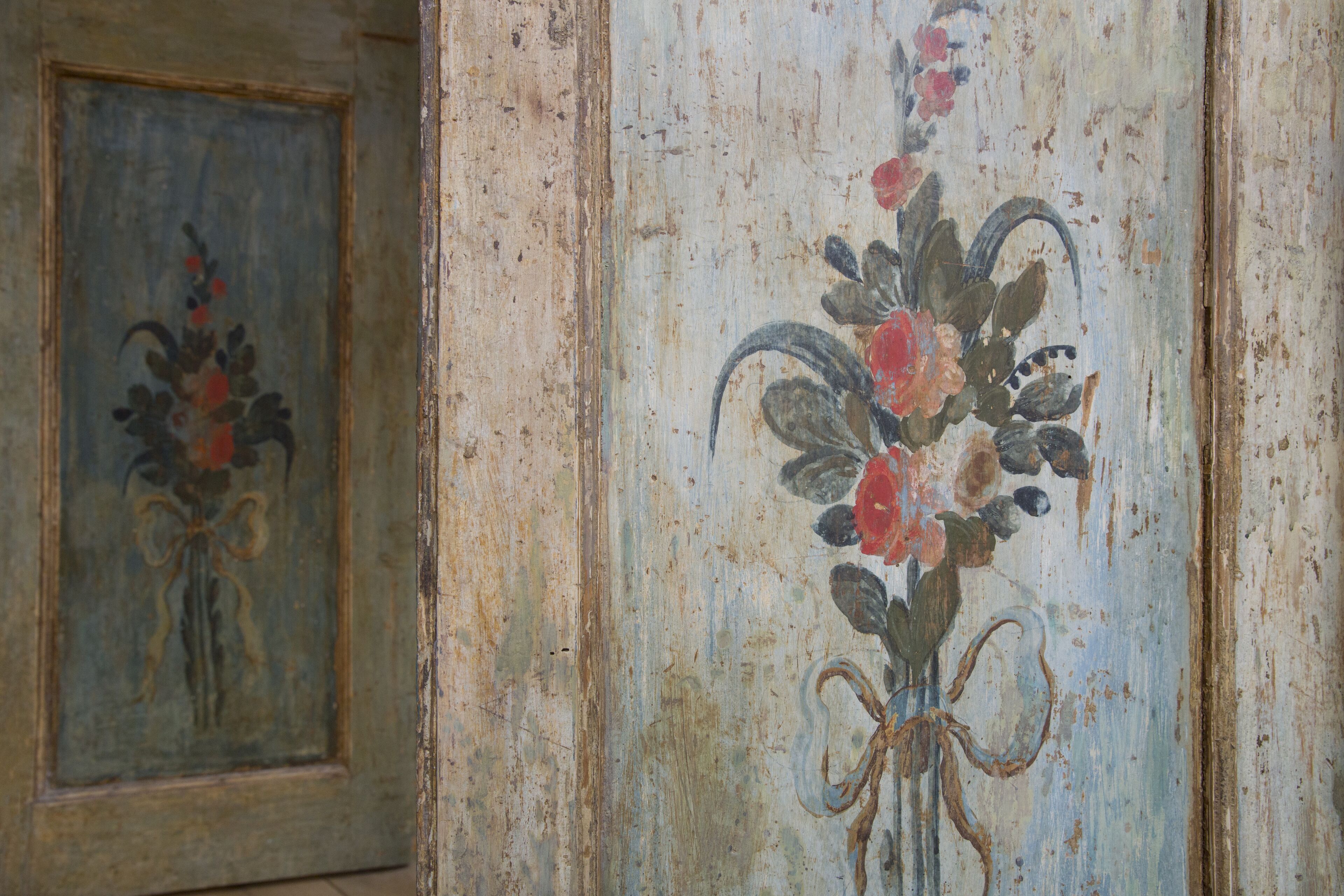 Un mur orné d’une fresque florale et d’un miroir encadré.