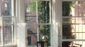 A room with a round table and four chairs, large windows with white shutters, and a view of greenery outside. - Elegant Back Bay Brownstone-Comm Av 1+ Bed - 1 Week Min, beyond 2 wks considered (Boston)