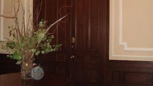 A room with a wooden door, a round wooden table with a vase of plants, and a chandelier. - Elegant Back Bay Brownstone-Comm Av 1+ Bed - 1 Week Min, beyond 2 wks considered (Boston)