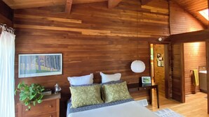 Un dormitorio de cabaña de madera con una cama, una mesita de noche, un aparador y un cuadro en la pared.