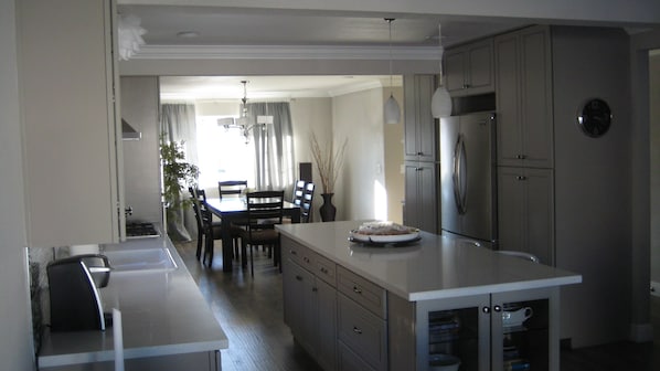 Una cocina moderna con una isla central, electrodomésticos integrados y un comedor con candelabro.