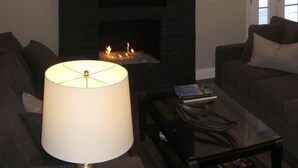 Un salon avec une cheminée, un téléviseur fixé au-dessus et un canapé.